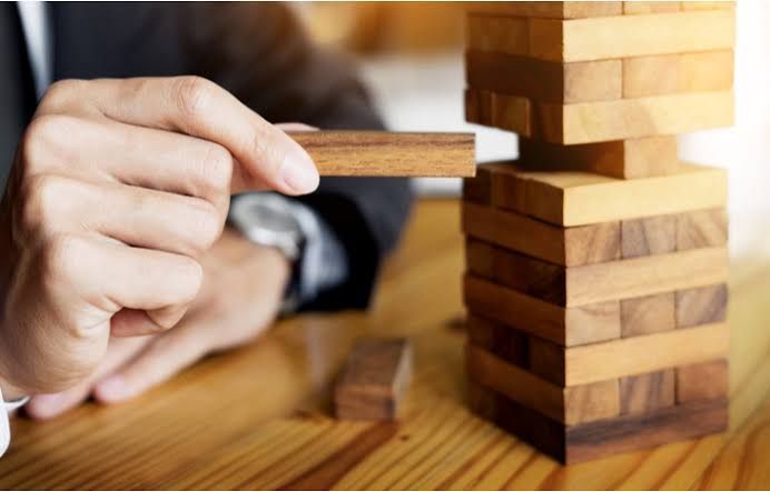 Hand placing a block into a Jenga tower on a wooden table