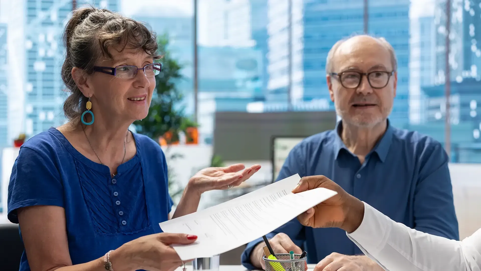 Two people reviewing a tablet together at a bright table with charts and a coffee mug