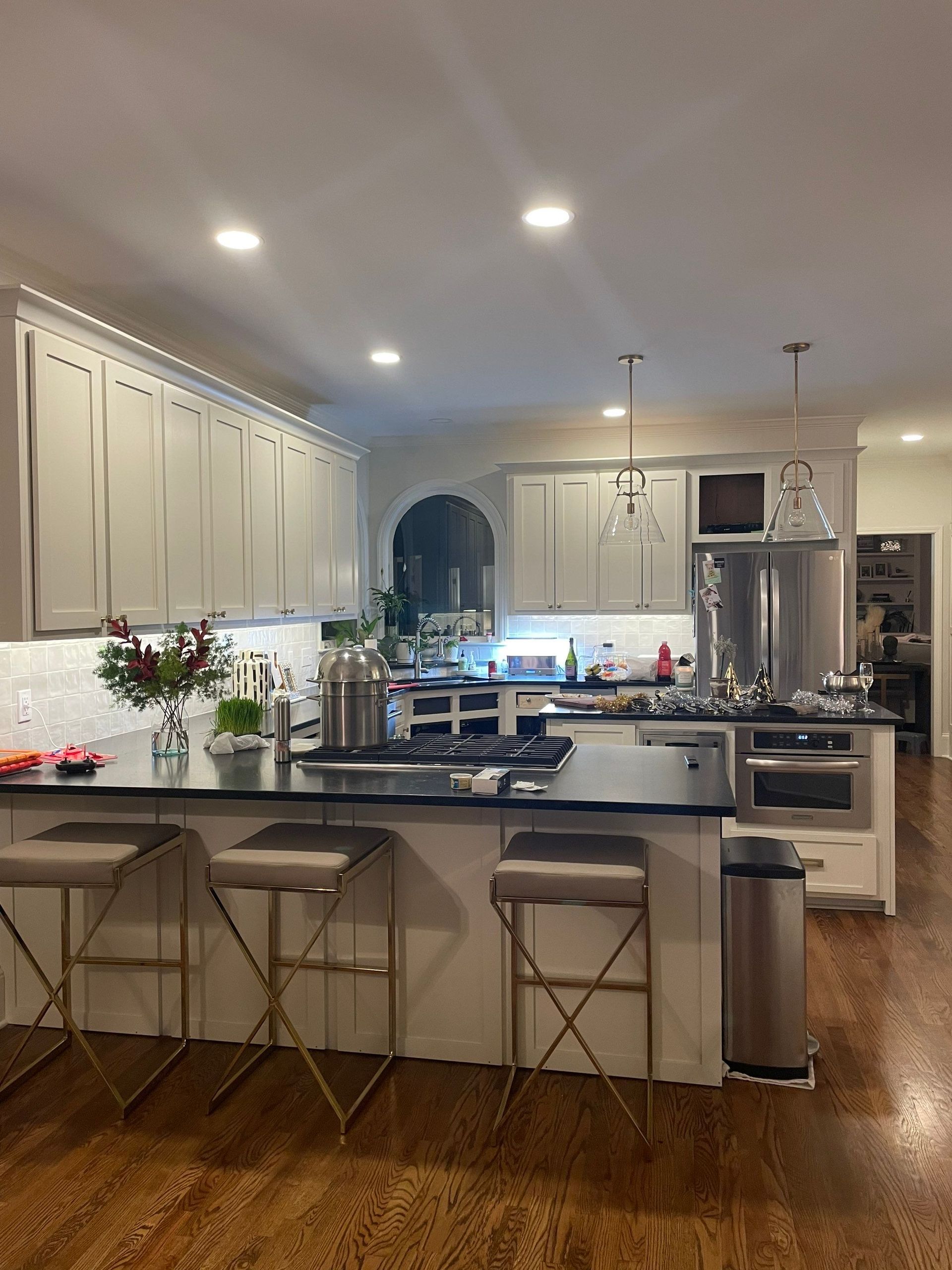 A kitchen with white cabinets and stools and a large island.