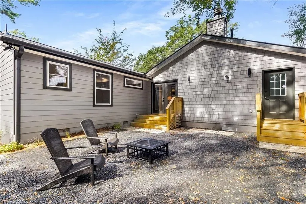 A house with a fire pit and chairs in front of it.