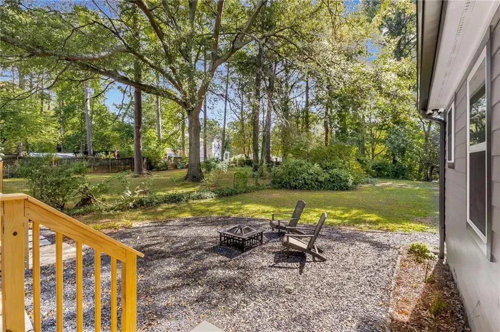 A patio with chairs and a fire pit in the backyard of a house.