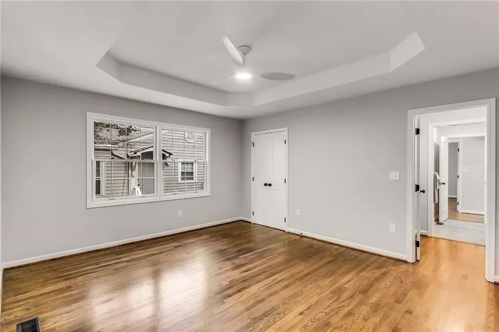 An empty living room with hardwood floors and a ceiling fan.