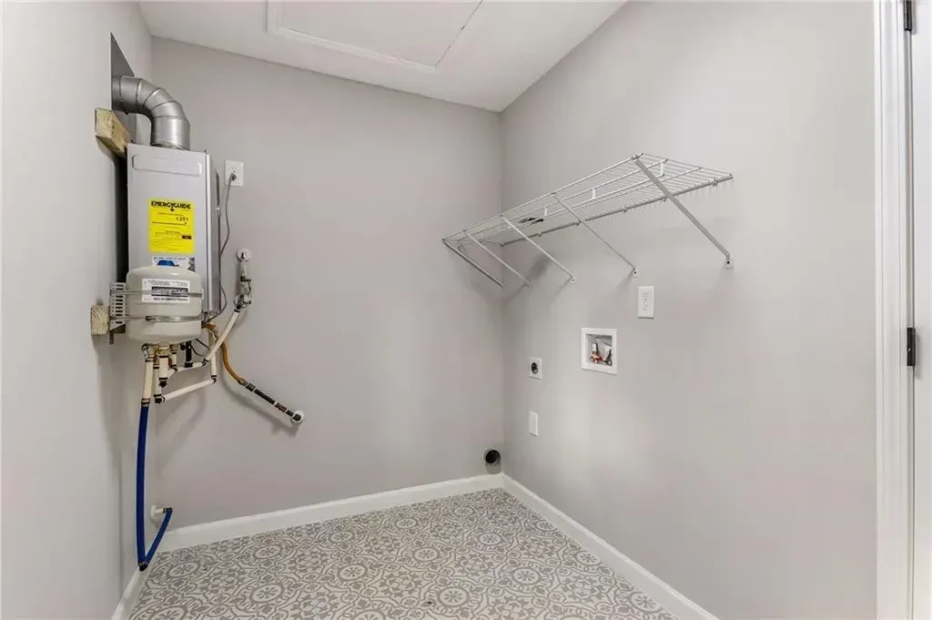A laundry room with a water heater hanging on the wall.