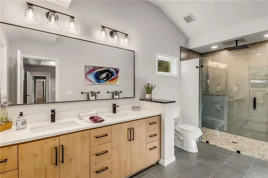 A bathroom with two sinks , a toilet , and a walk in shower.
