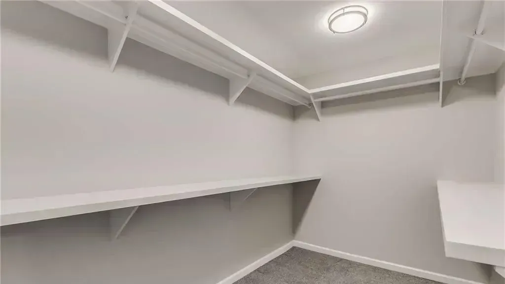 An empty walk in closet with shelves and a light on the ceiling.