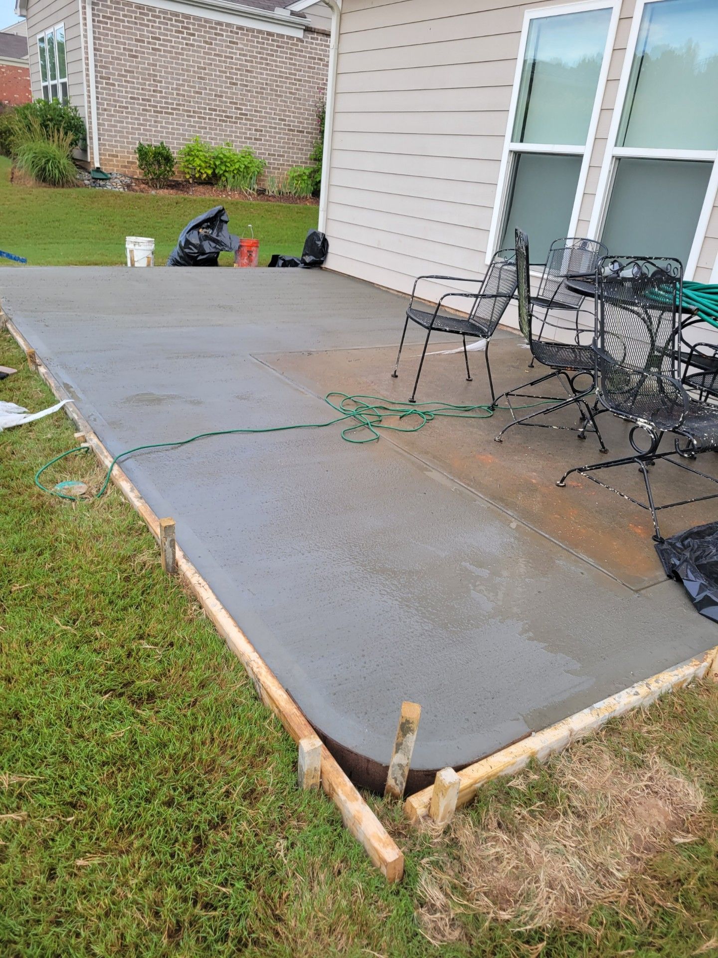 A patio with a table and chairs is being built in front of a house.