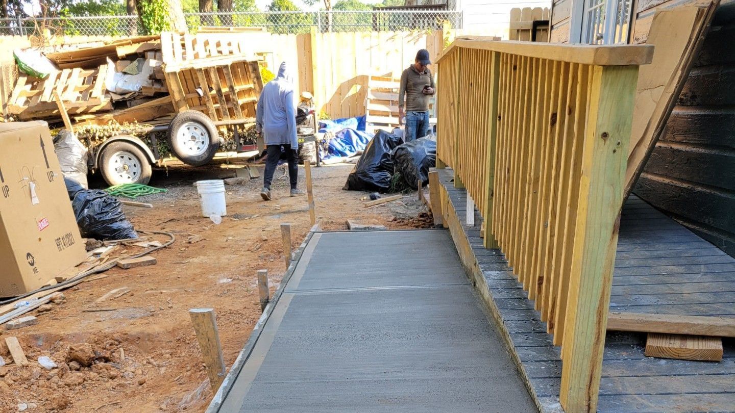 A concrete walkway is being built next to a wooden deck.