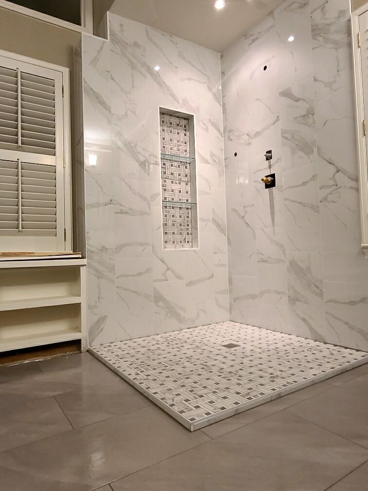 A bathroom with marble walls and a walk in shower