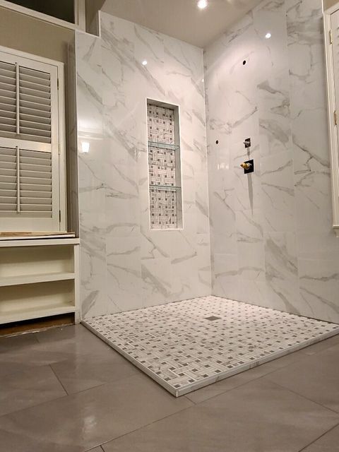 A bathroom with marble walls and a walk in shower