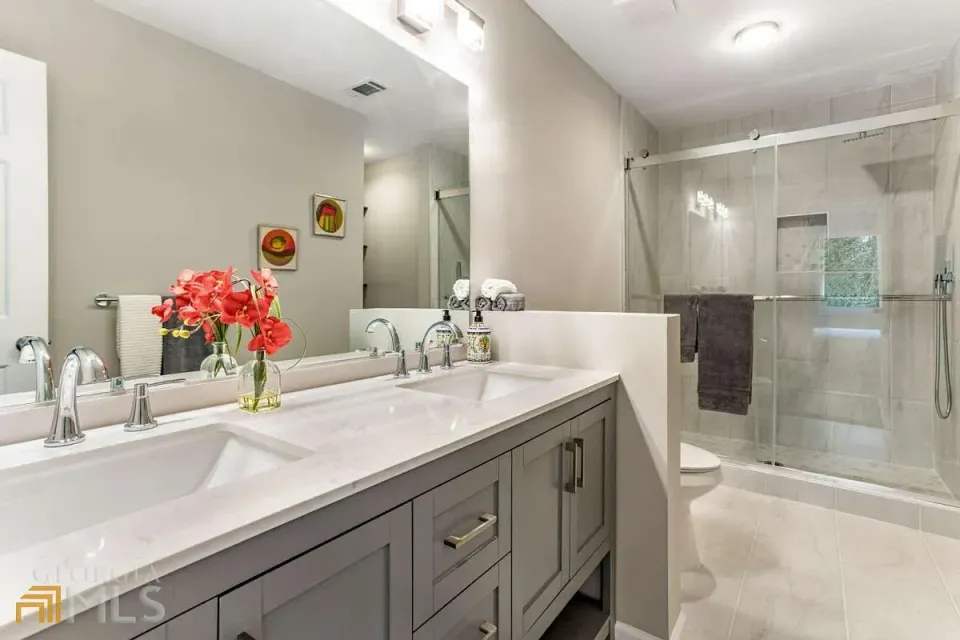 A bathroom with two sinks , a toilet and a shower.