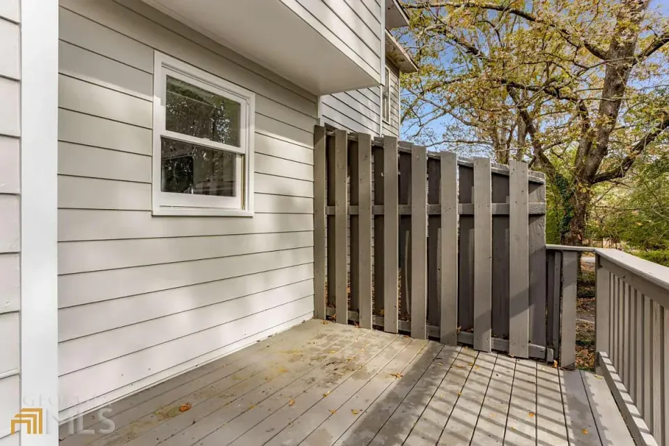 A white house with a wooden deck and fence.