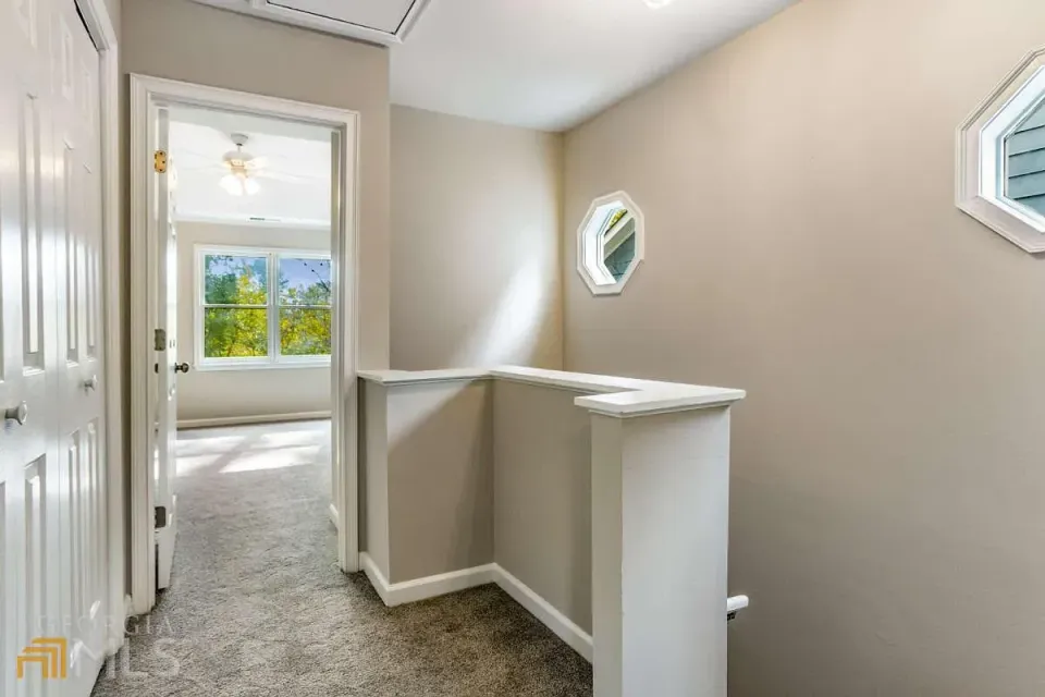 A hallway leading to a bedroom and a staircase in a house.