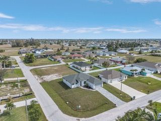 Aerial view of a suburban neighborhood with houses, streets, and blue sky.