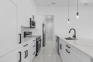 White kitchen with stainless steel appliances and black hardware.