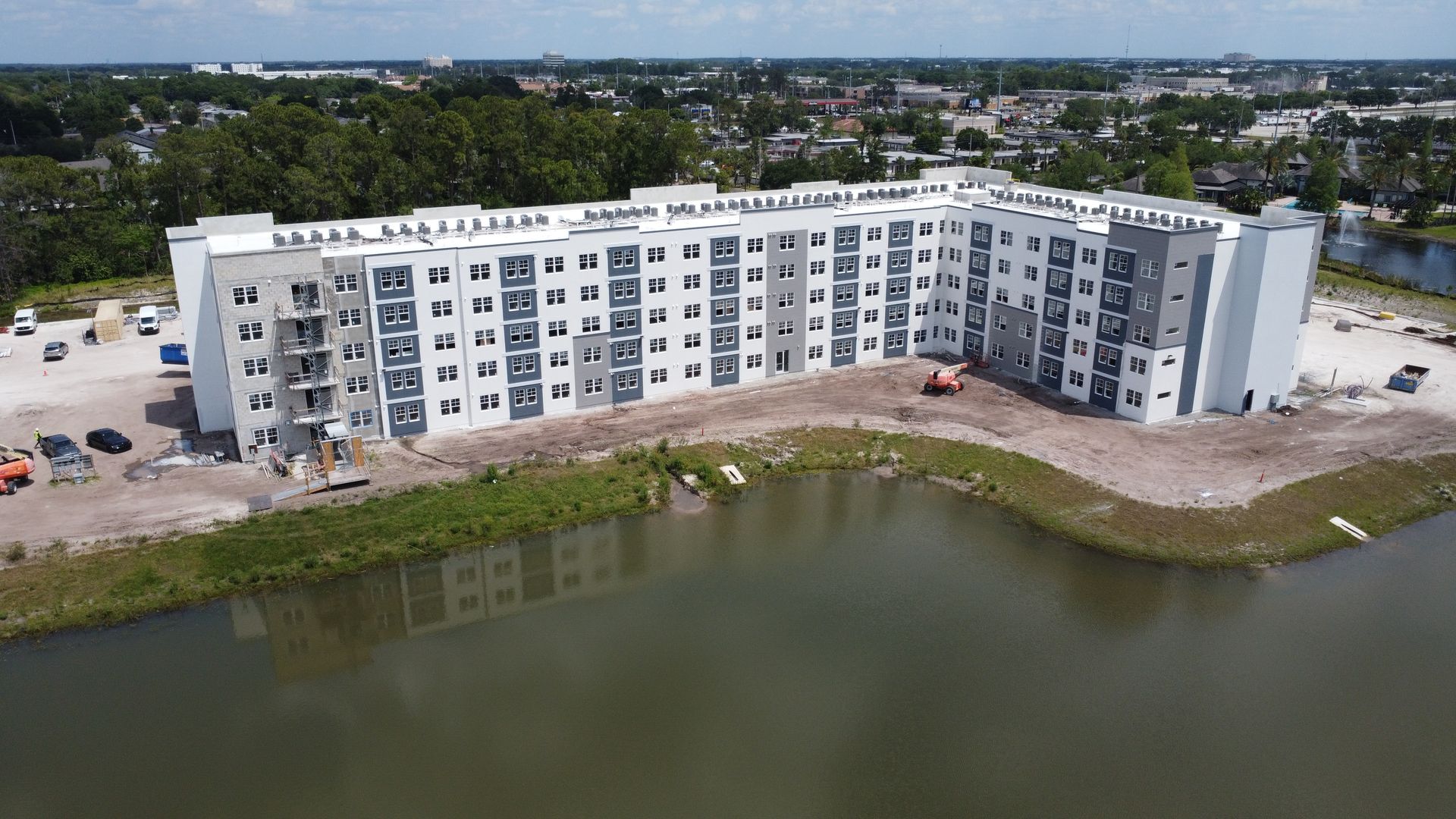An aerial view of a large apartment building under construction next to a lake.