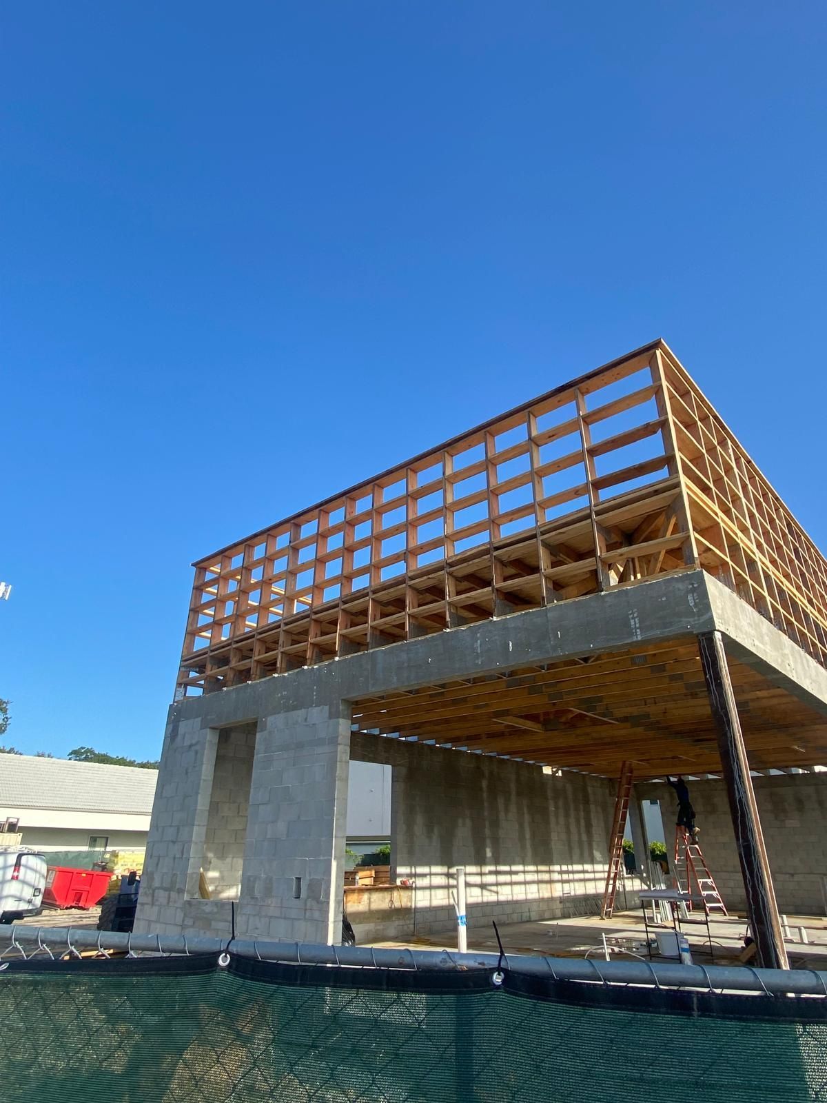 Building under construction; concrete base with wooden frame and clear blue sky.