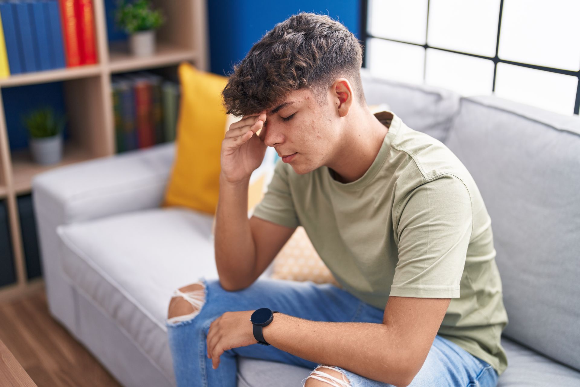 teen boy with headache sitting on couch
