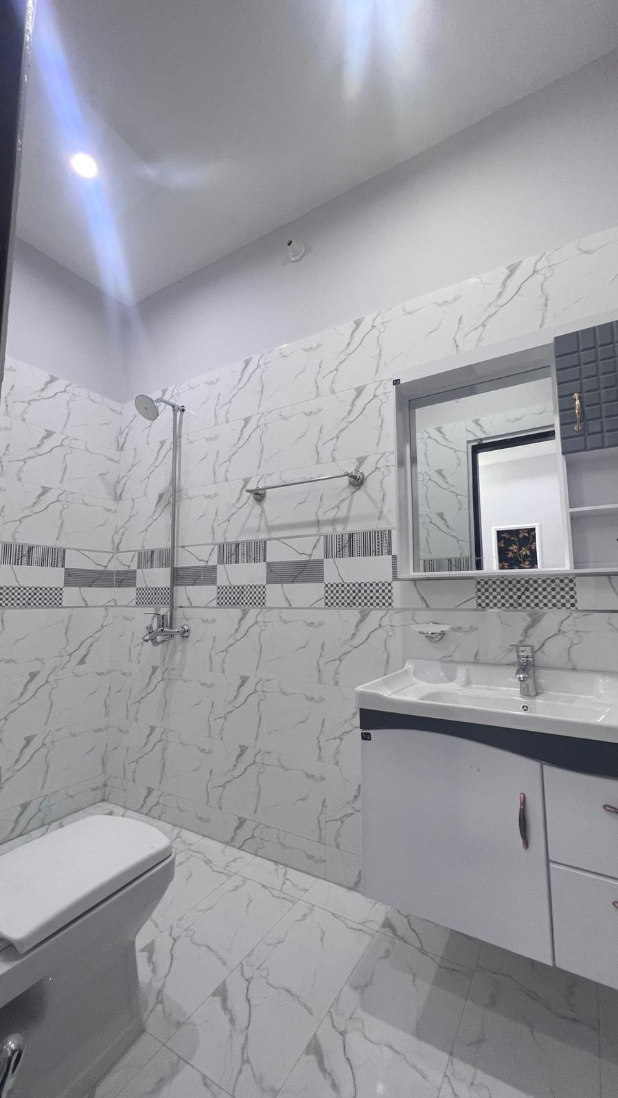 A bathroom with a toilet , sink , mirror and shower.