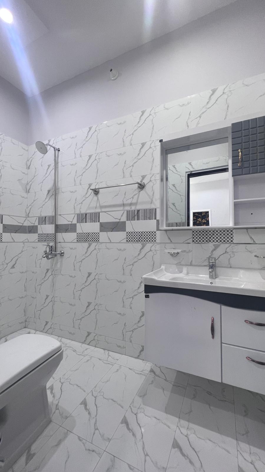 A bathroom with a toilet , sink , mirror and shower.