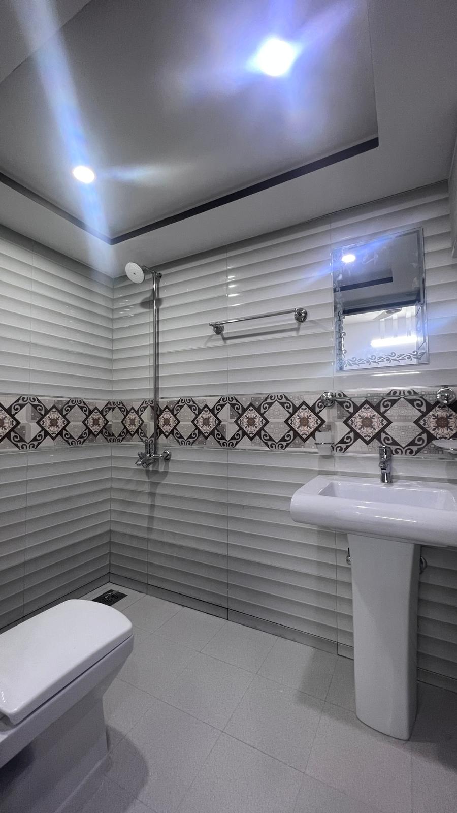 A bathroom with a toilet , sink , mirror and shower.