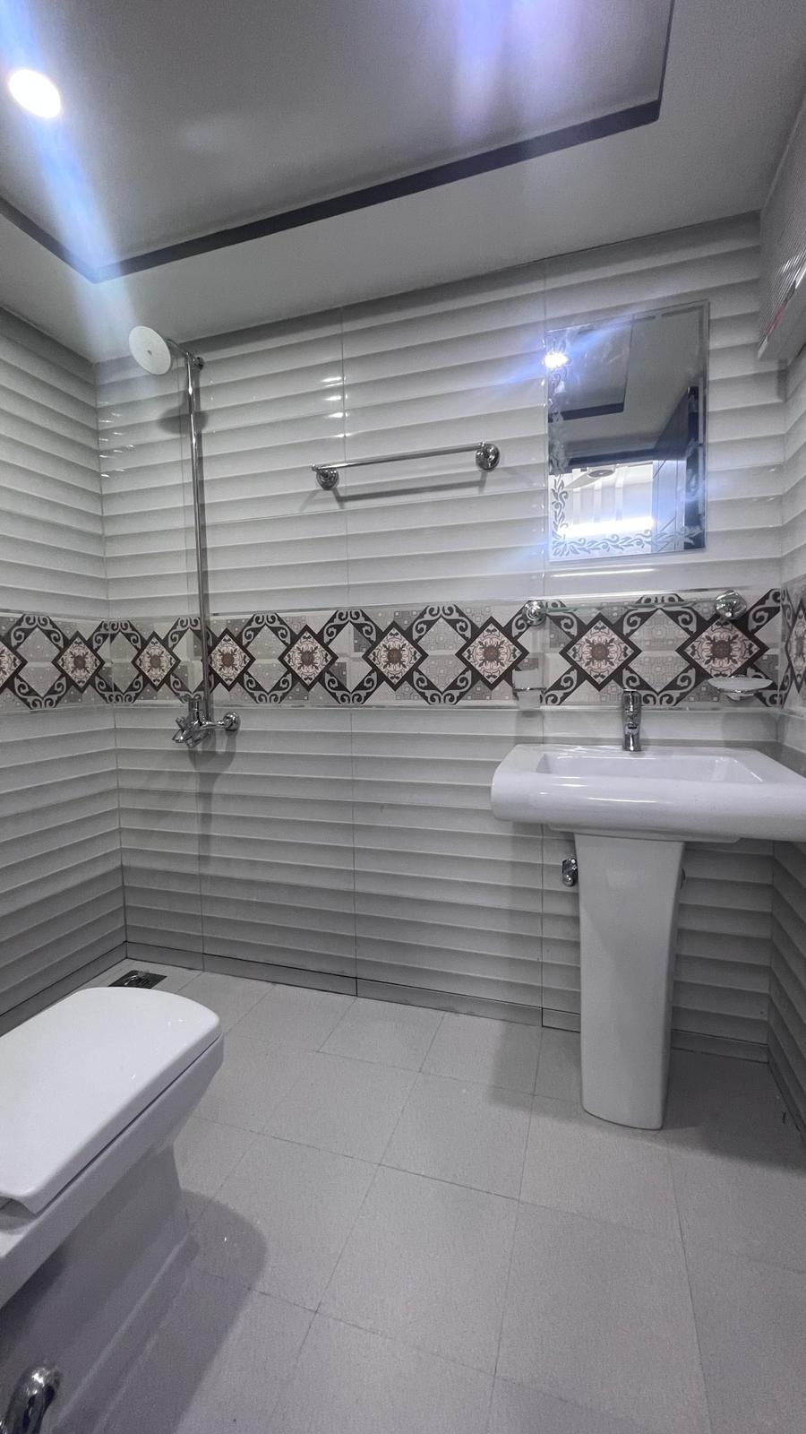 A bathroom with a toilet , sink and shower.