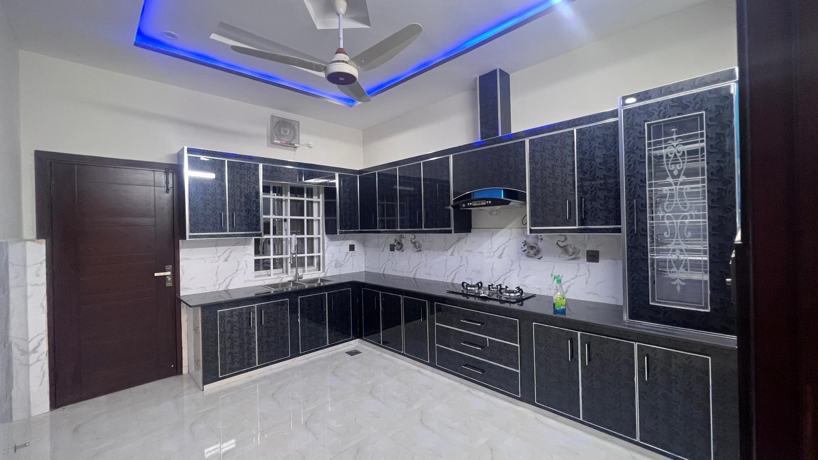 A kitchen with black cabinets and a ceiling fan.