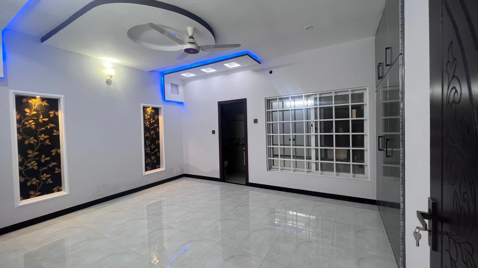 An empty living room with a ceiling fan and a door.