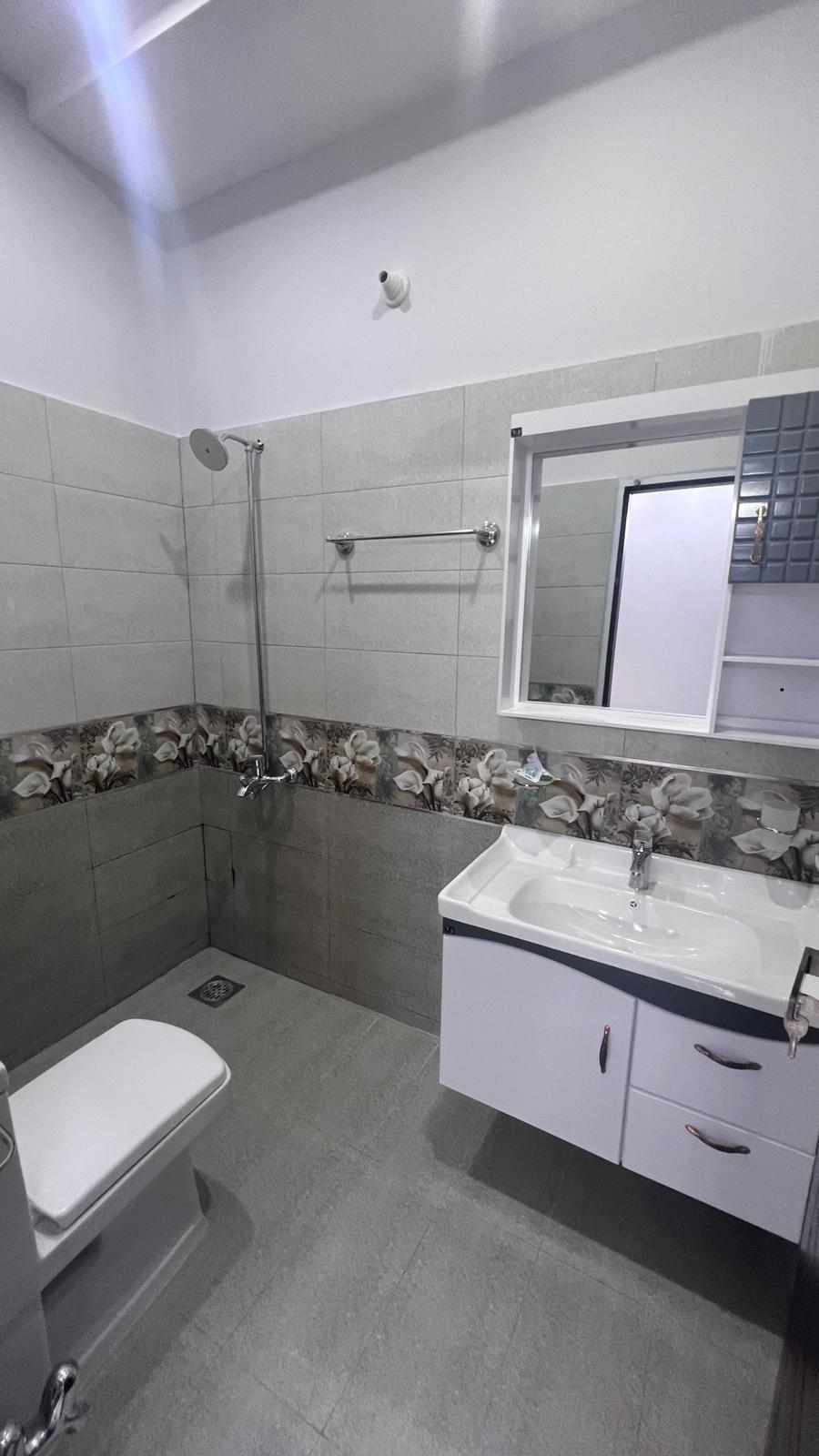 A bathroom with a toilet , sink , mirror and shower.