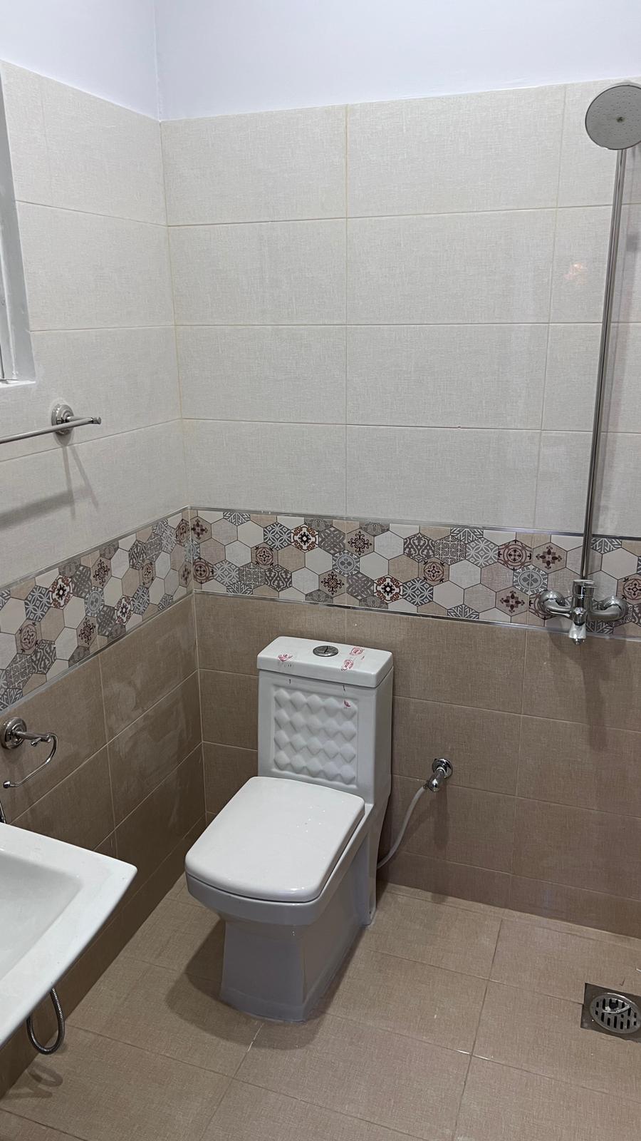 A bathroom with a toilet , sink and shower.