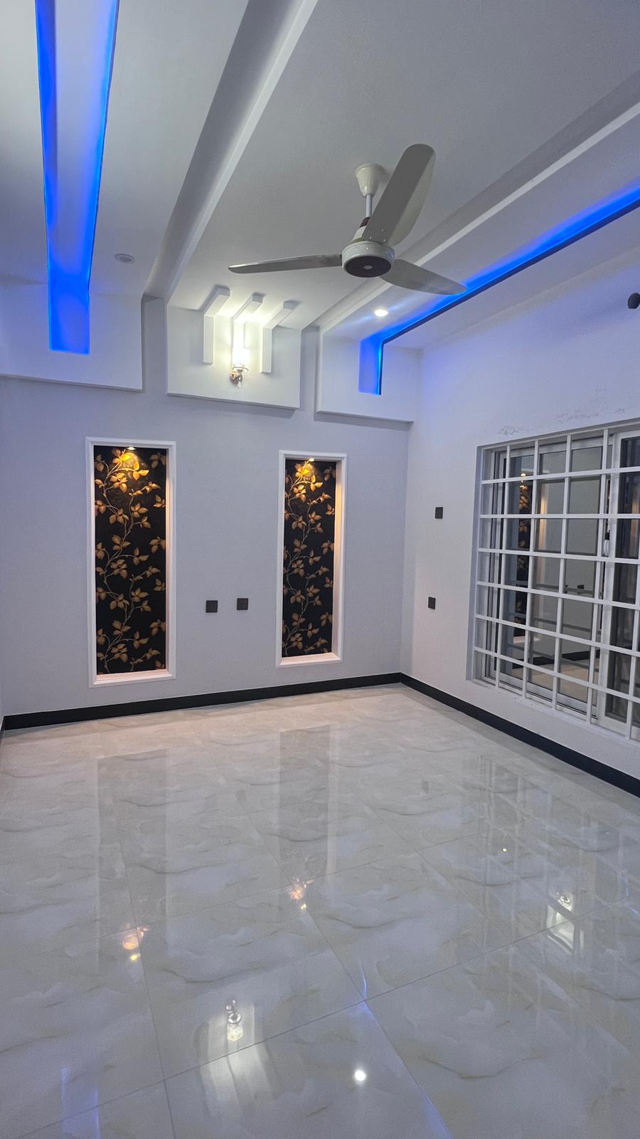 An empty room with a ceiling fan and blue lights.