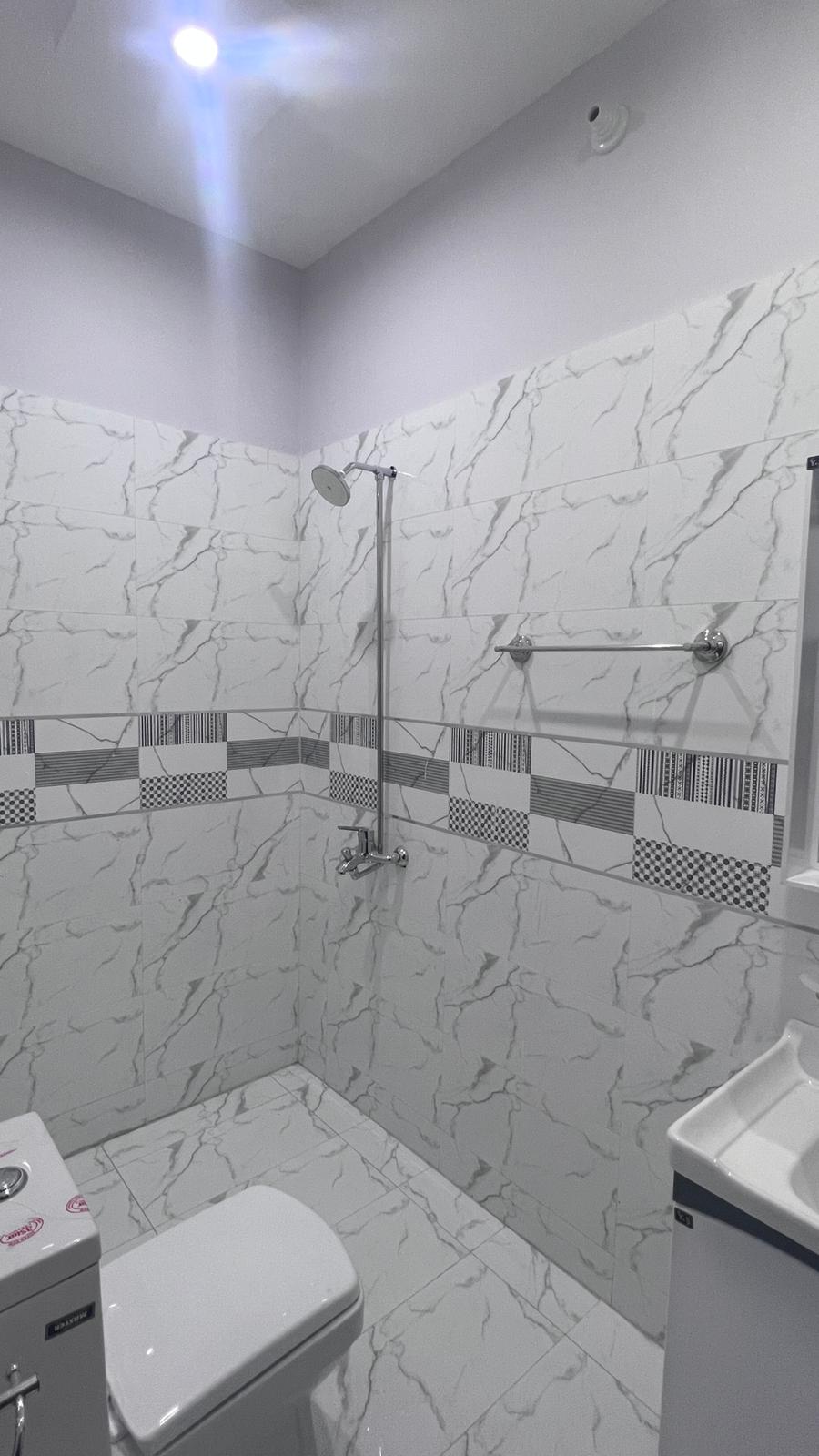 A bathroom with a toilet , sink and shower.