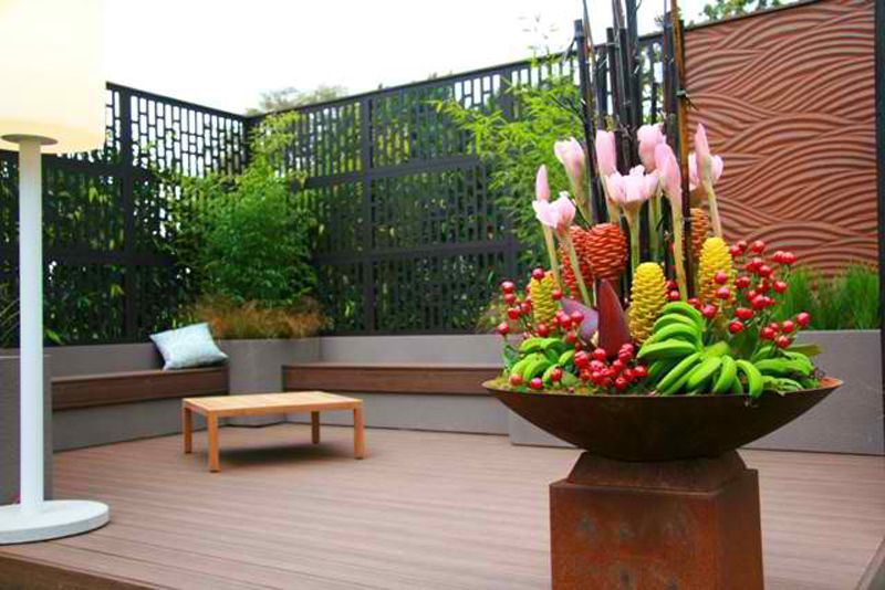 A Large Bowl Filled With Flowers is on a Wooden Deck — B & B Timbers Ballina In West Ballina, NSW