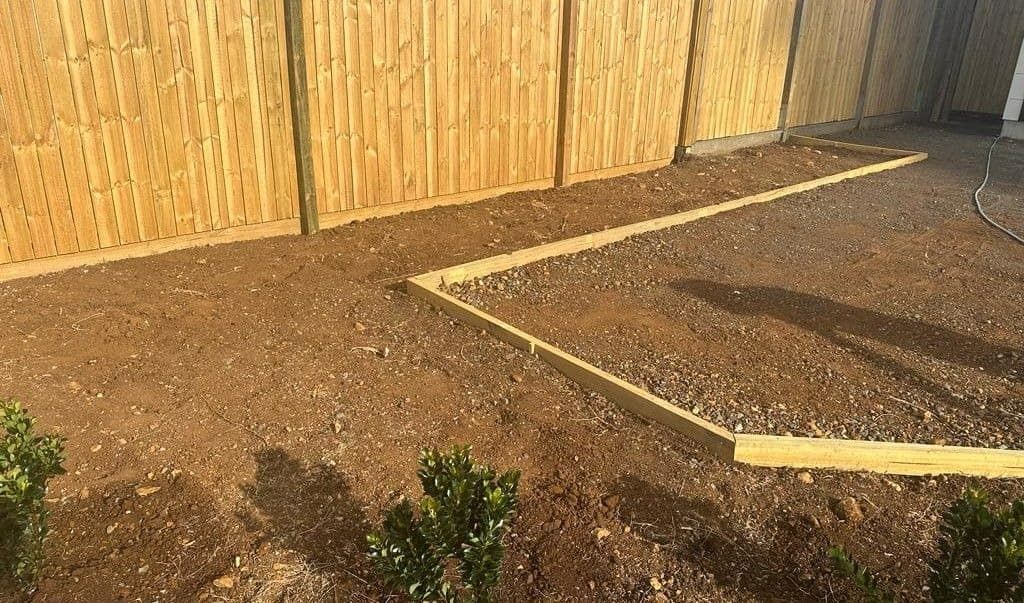 A Wooden Fence is Surrounded by Gravel and Shrubs in a Yard — B & B Timbers Ballina In West Ballina, NSW