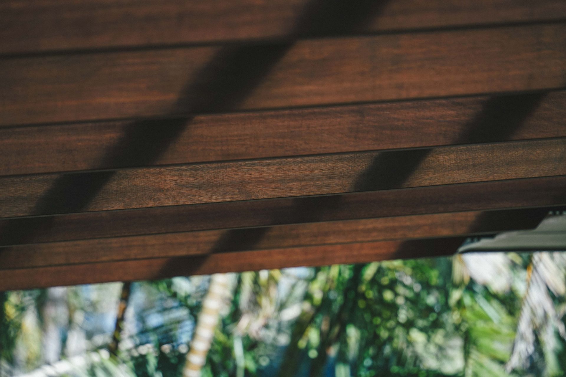 Wooden pergola casting shadows over a blurred green garden below — B & B Timbers Ballina In West Ballina, NSW