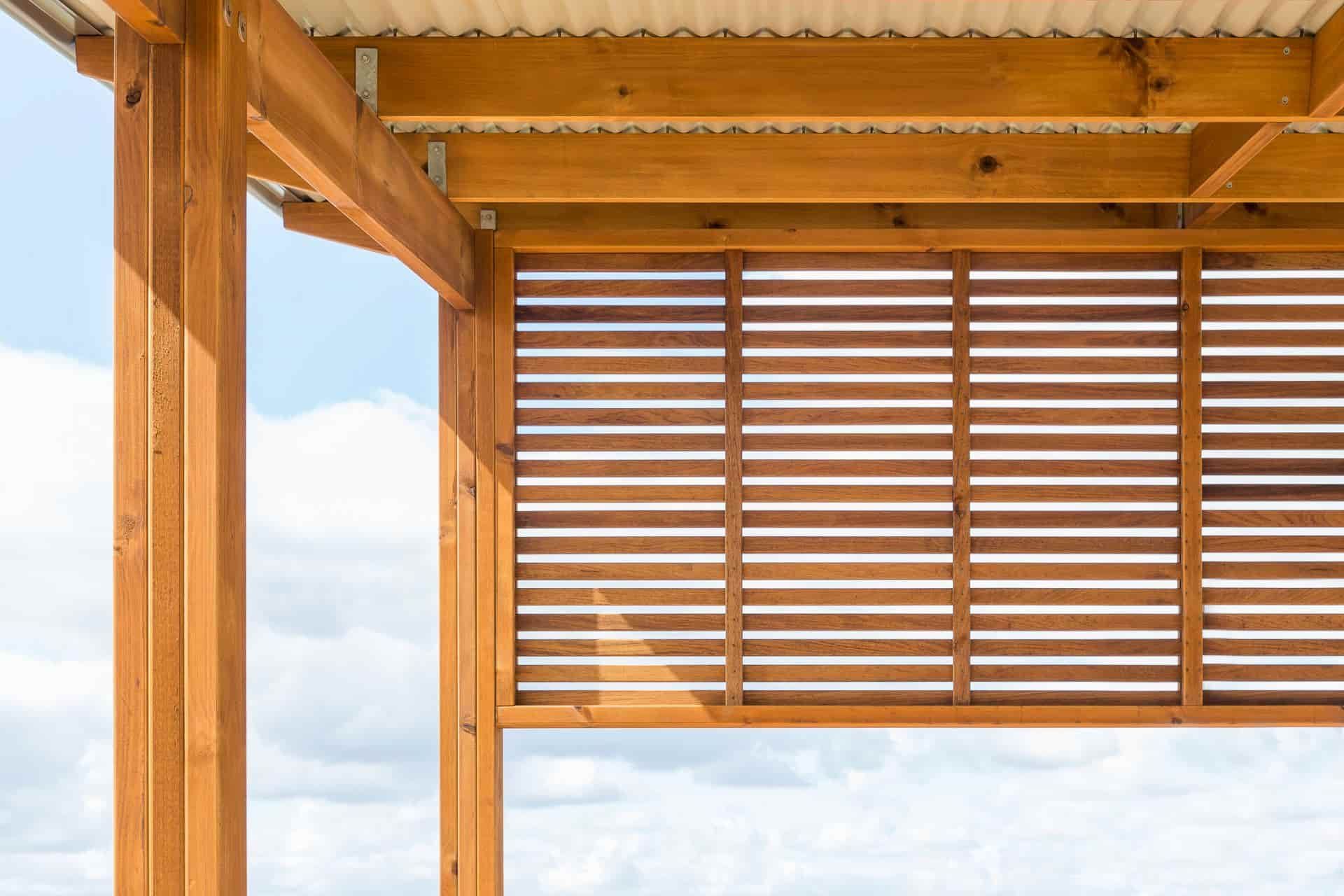 Wooden pergola with horizontal slatted shade panel against a bright blue sky — B & B Timbers Ballina In West Ballina, NSW
