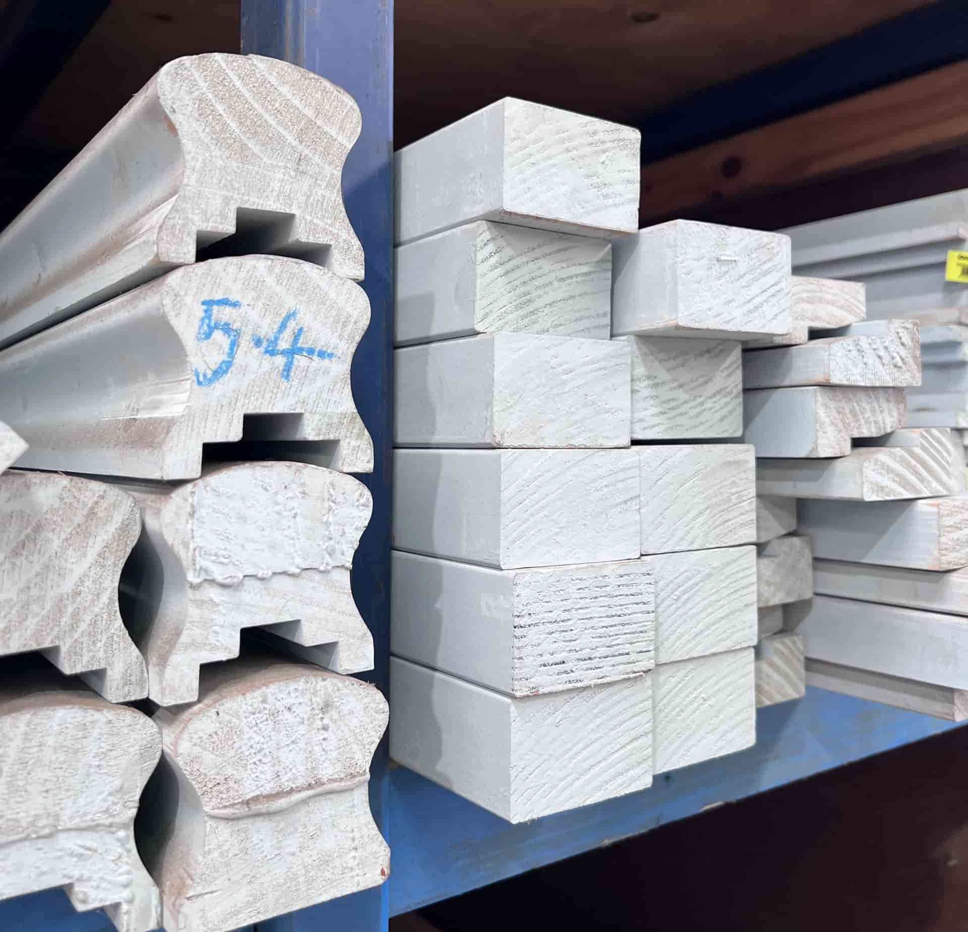 Stacks of white-painted wood moldings and trim boards stored on a warehouse shelf. — B & B Timbers Ballina In West Ballina, NSW