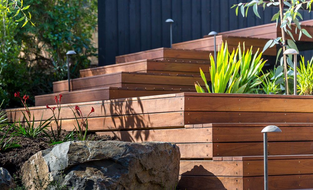 A Set of Wooden Stairs Leading Up to a House Surrounded by Plants and Rocks — B & B Timbers Ballina In West Ballina, NSW