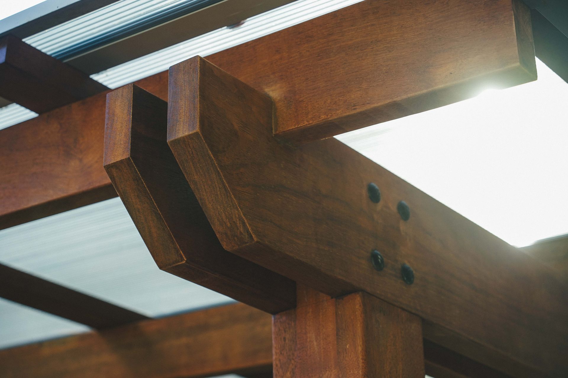 Wooden pergola beams with translucent roof panels and bright sunlight — B & B Timbers Ballina In West Ballina, NSW