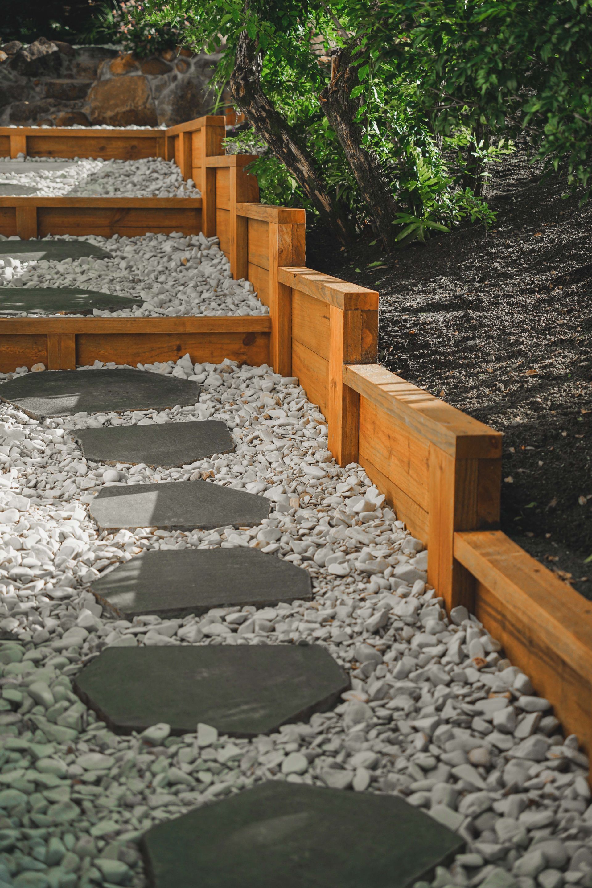 Stepping stone path beside white gravel and a wooden fence in a shaded garden — B & B Timbers Ballina In West Ballina, NSW