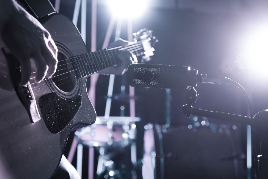 A person is playing an acoustic guitar on a stage.