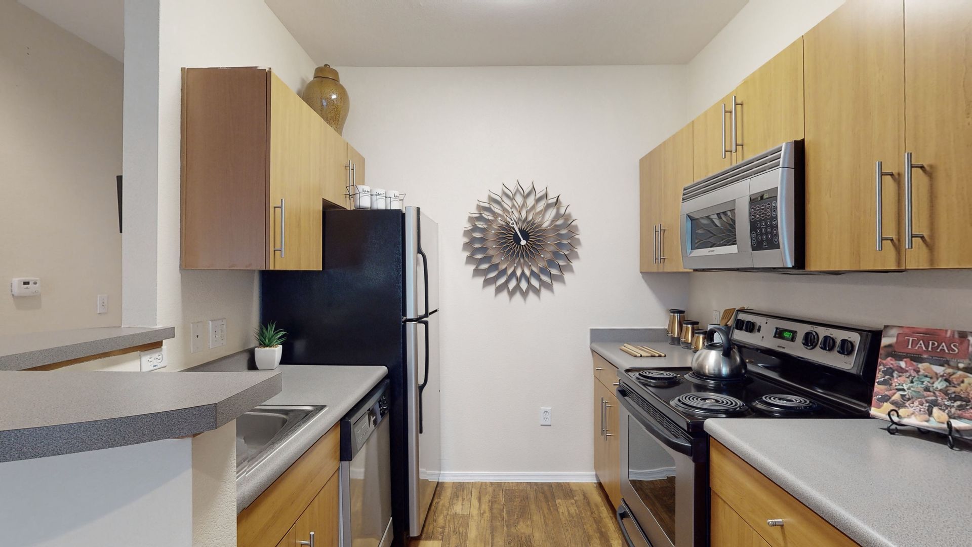 A kitchen with wooden cabinets , stainless steel appliances , and a black refrigerator.