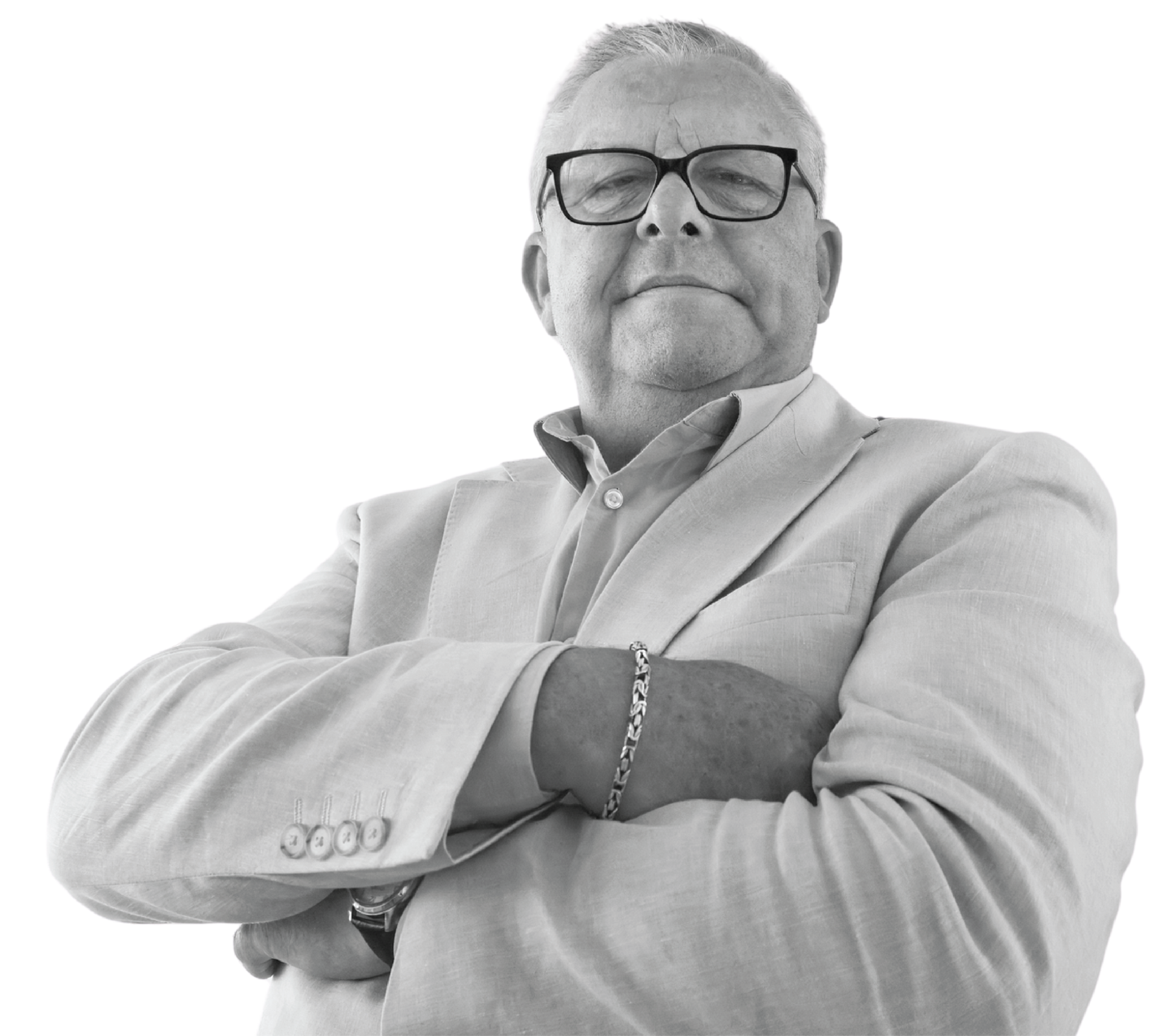 Man in a light blazer, arms crossed, wearing glasses, looking towards the viewer.