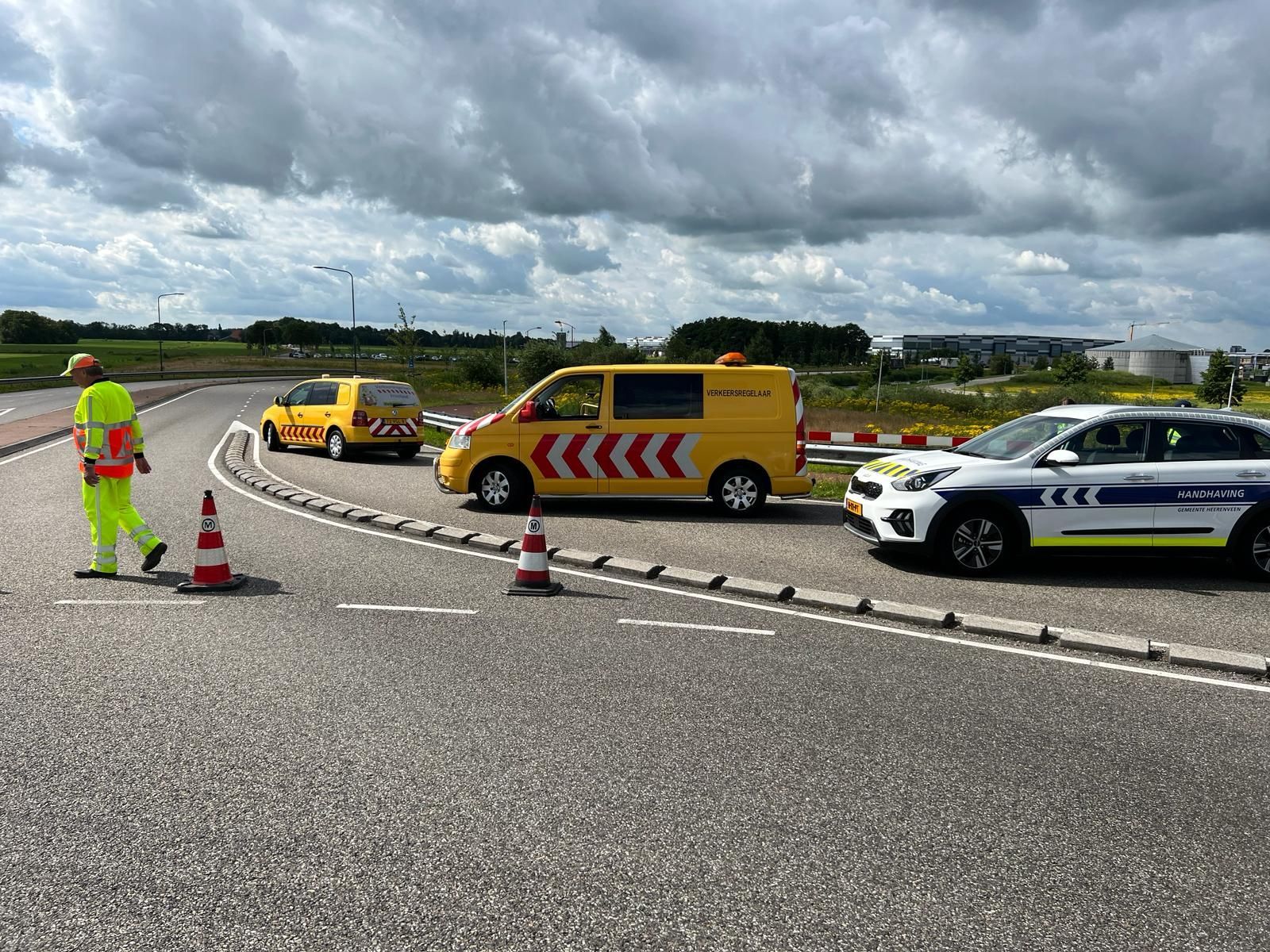 Een geel busje en een witte auto staan ​​langs de kant van de weg geparkeerd.