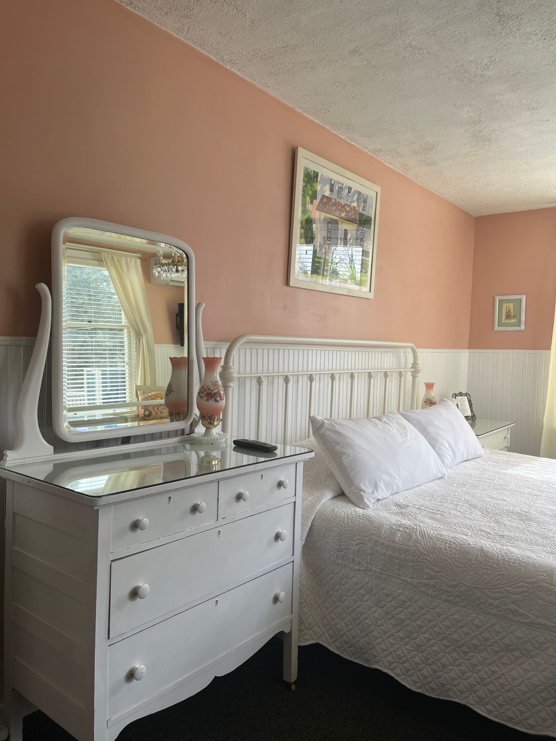 A bedroom with a bed , dresser and mirror