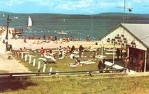 A group of people are sitting on the beach near a building.