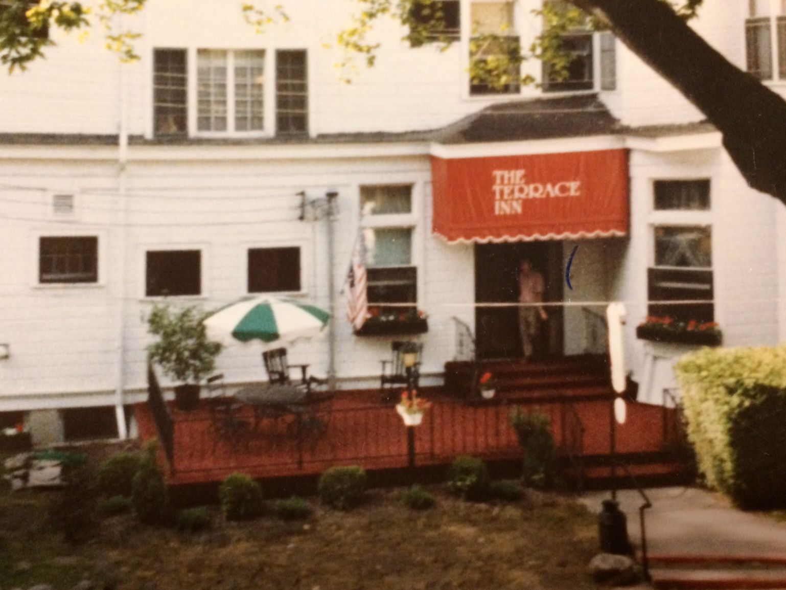 A white building with a red awning that says the terrace inn