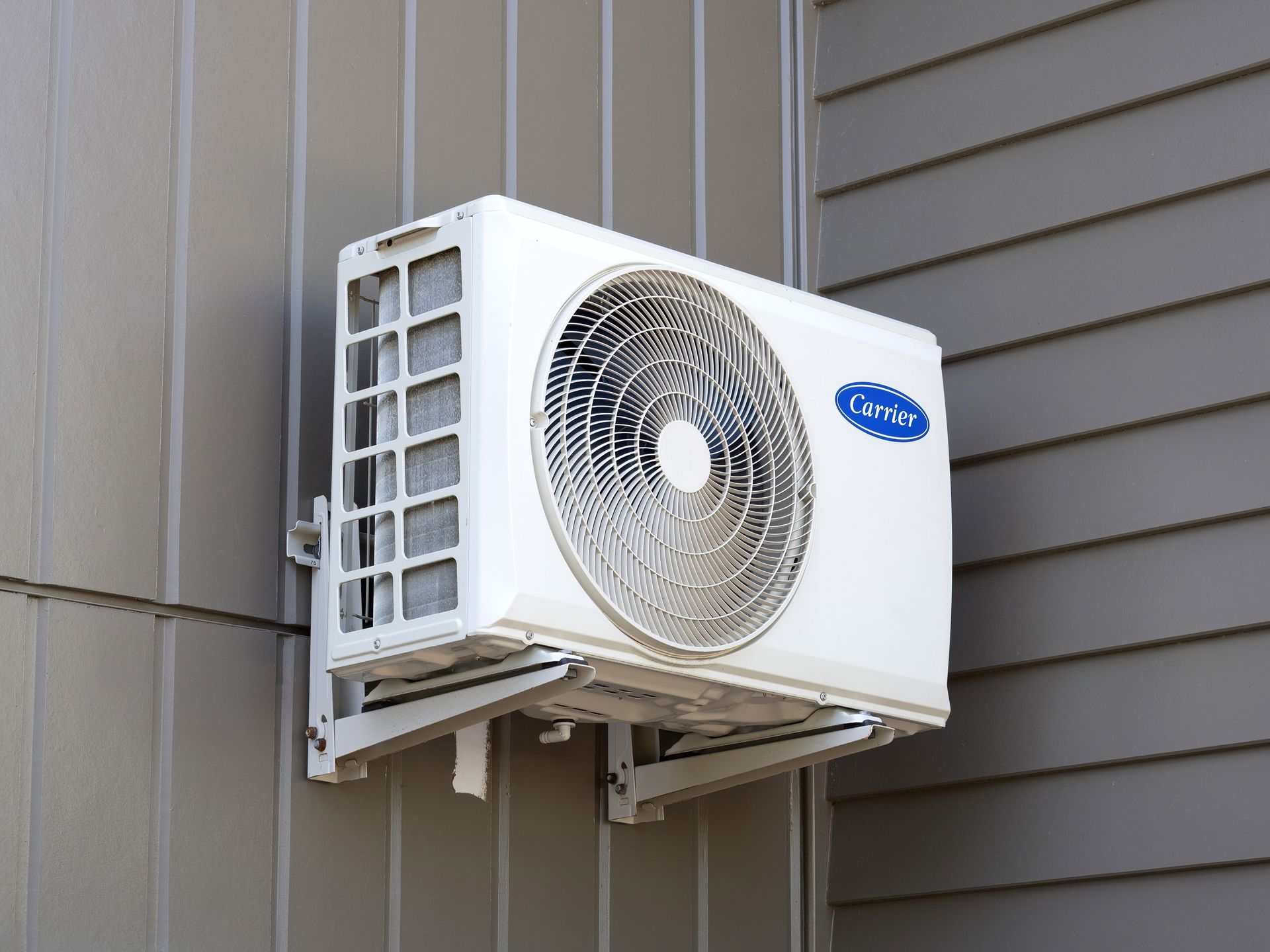 Outdoor wall-mounted Carrier air conditioner unit on a house exterior.