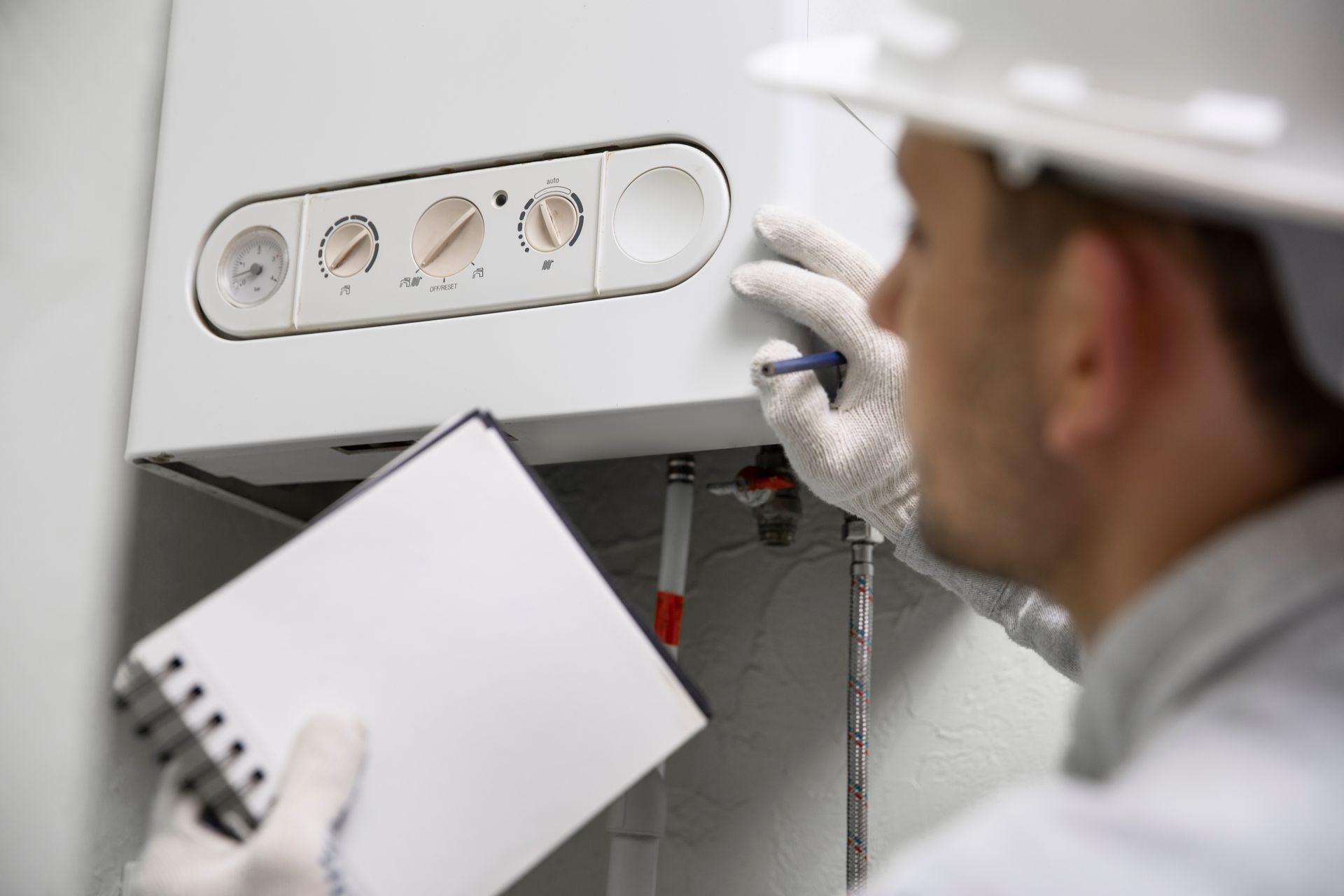 Technician inspecting a wall-mounted boiler with clipboard and wrench