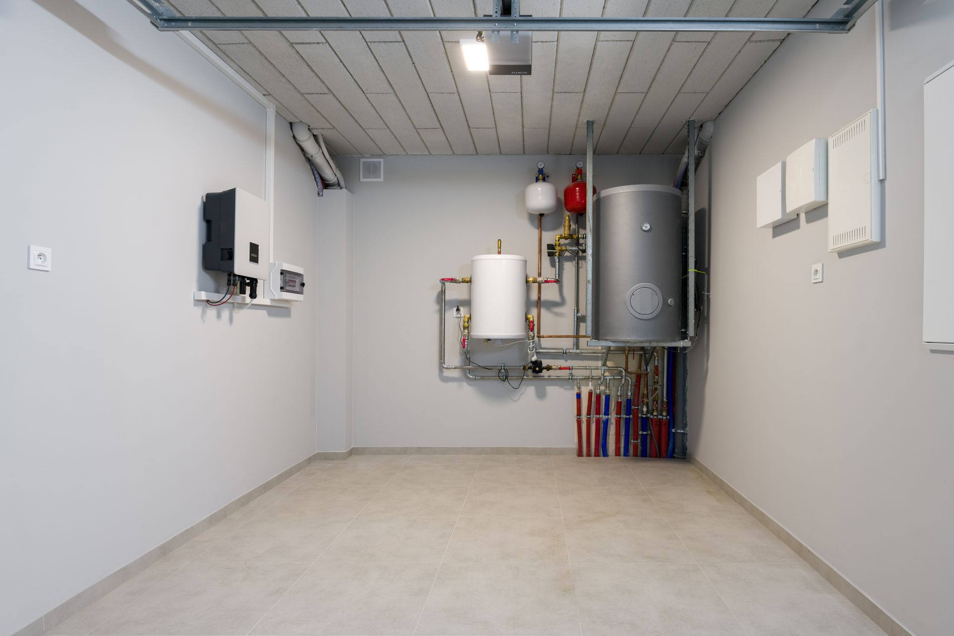 Empty utility room with boiler, water heater, pipes, and electrical panels