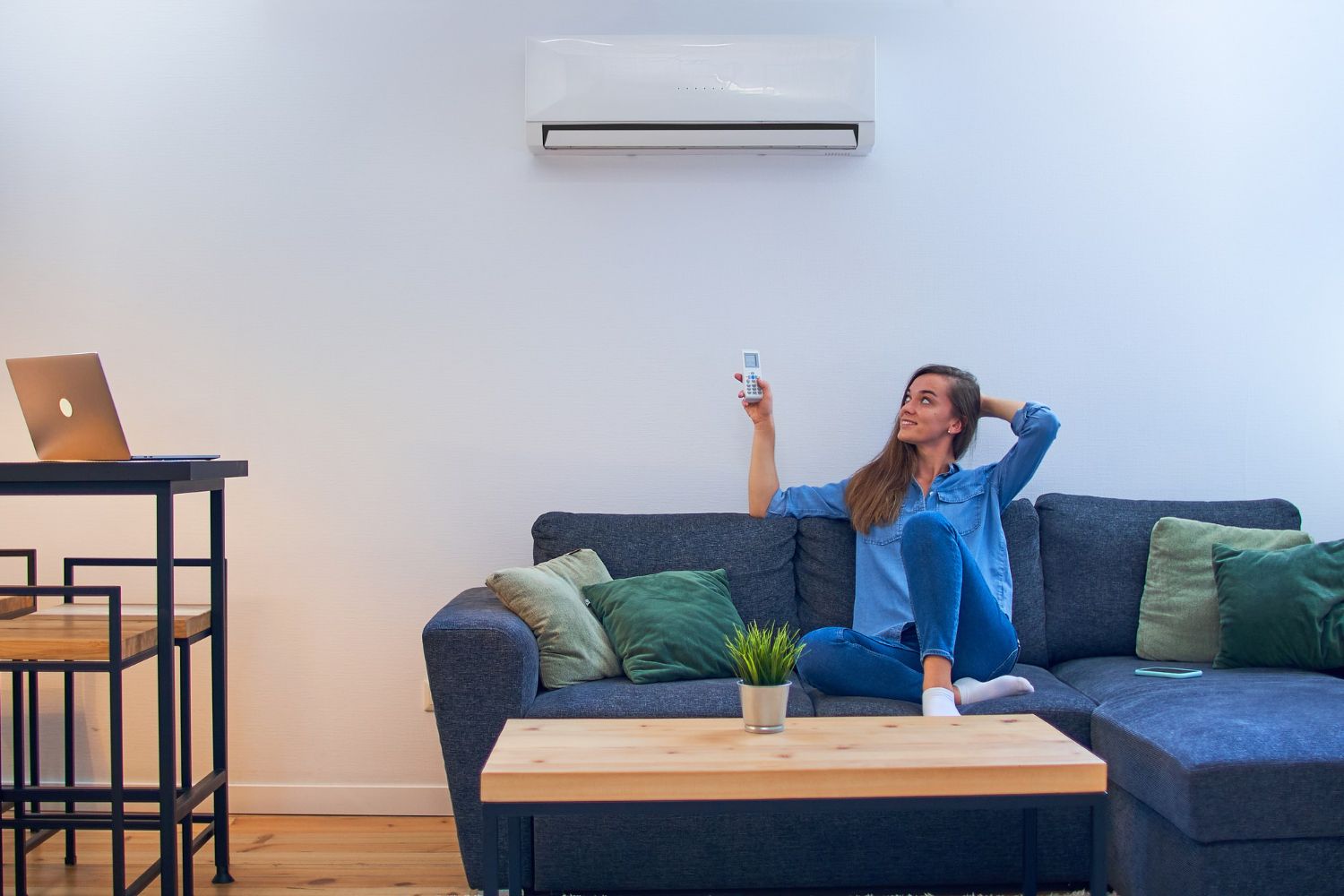 A woman is sitting on a couch in a living room holding a remote control.